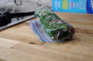 Photo showing how to roll bag of greens to remove air for freezing